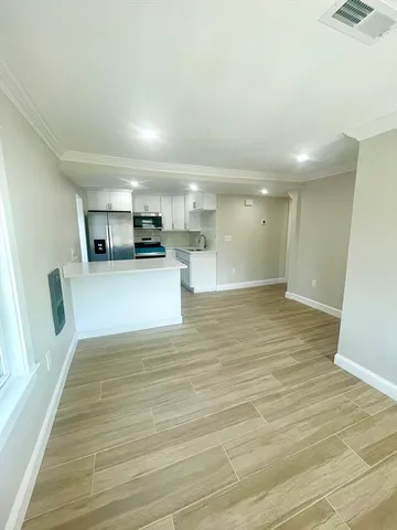 a view of kitchen and empty room with wooden floor