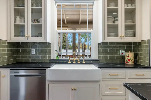 a kitchen with stainless steel appliances granite countertop a stove a sink dishwasher a microwave oven and white cabinets with wooden floor