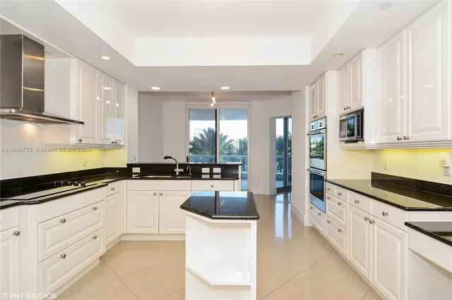 a large white kitchen with stainless steel appliances granite countertop a lot of counter space and a sink