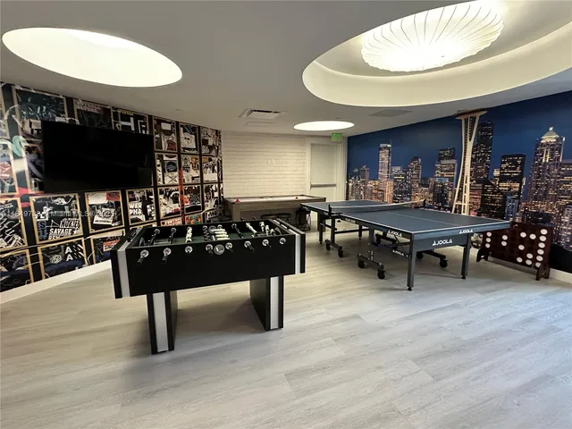 a view of a chandelier in big room with wooden floor and windows