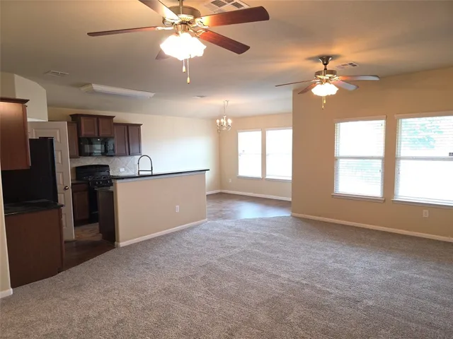 a view of a kitchen with a stove cabinets a ceiling fan and wooden floor
