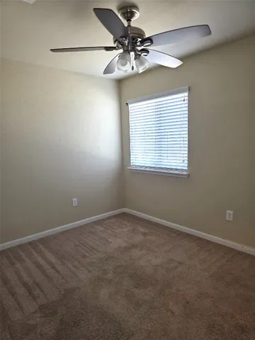 an empty room with a window and a fan