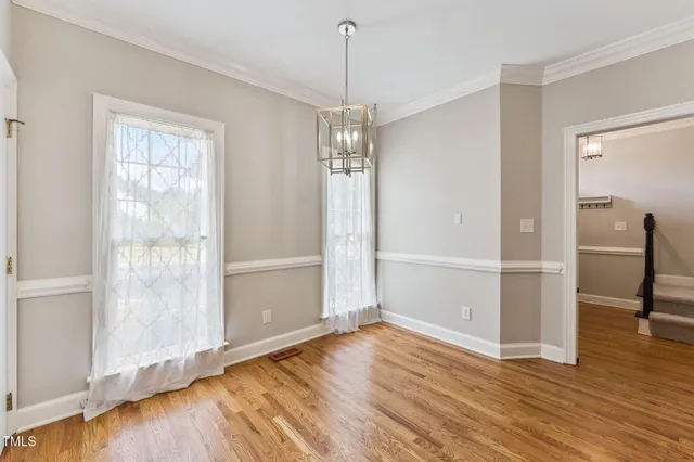 a view of an empty room with wooden floor fireplace and a window