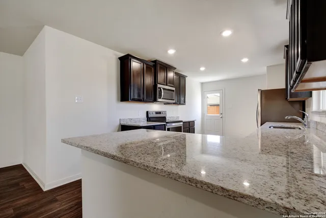 a large kitchen with granite countertop a sink and a stove top oven