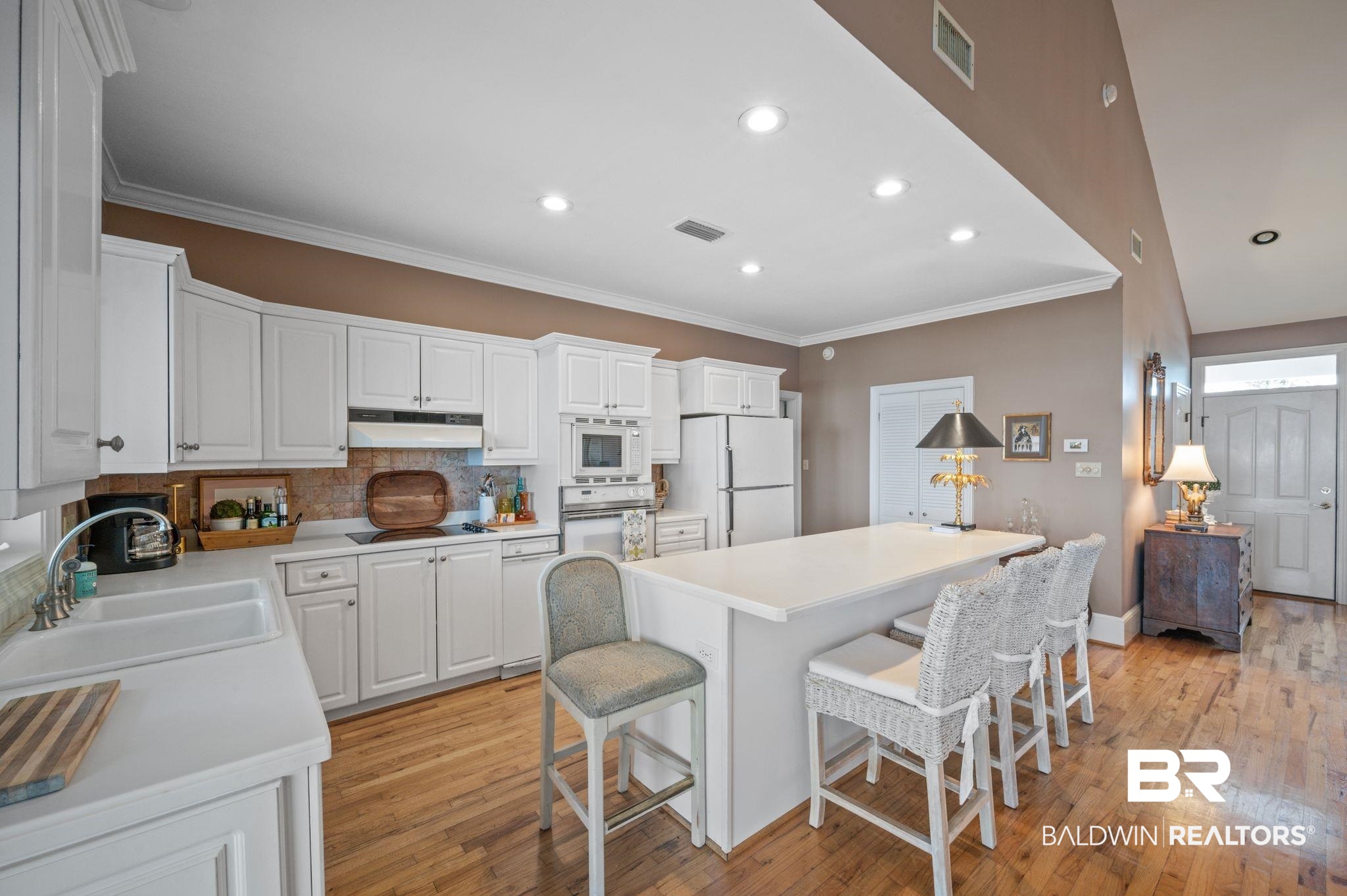 31800 River Road Orange Beach, AL 36561 - Photo 11 of 69 Kitchen with a center island, sink, white appliances, light hardwood / wood-style floors, and white cabinets