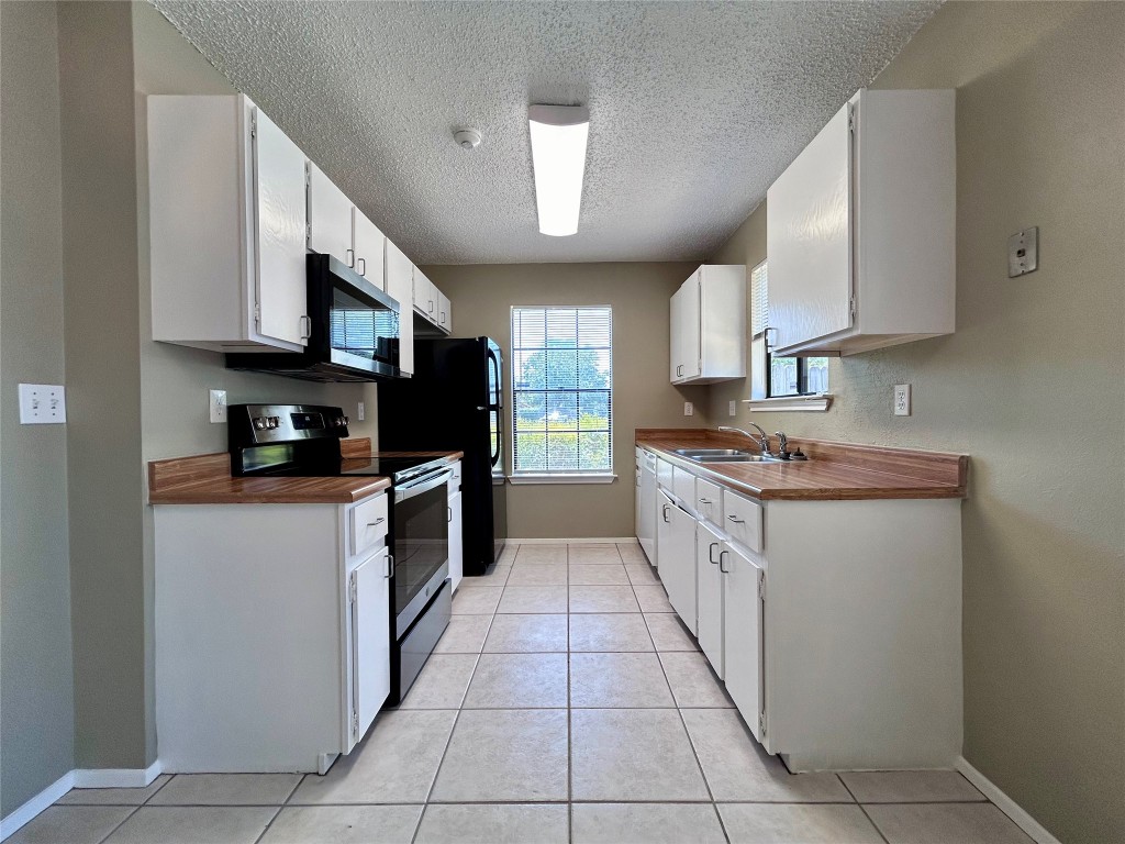 1908 Rainy Meadows Drive Austin, TX 78758 - Photo 6 of 17 a kitchen with stainless steel appliances granite countertop a stove a sink and a microwave