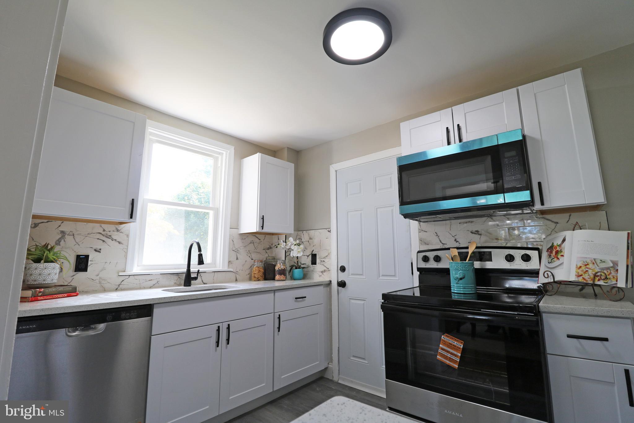 1016 Lamb Road Secane, PA 19018 - Photo 19 of 41 a kitchen with stainless steel appliances a stove a sink a microwave and cabinets