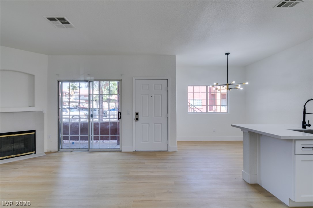 4730 East Craig Road, Unit 1085 Las Vegas, NV 89115 - Photo 21 of 23 Luminous living space featuring light wood flooring, a sleek fireplace, and a modern kitchen island, creating a harmonious open design.