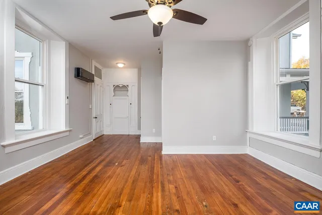 a view of a hallway with wooden floor and windows