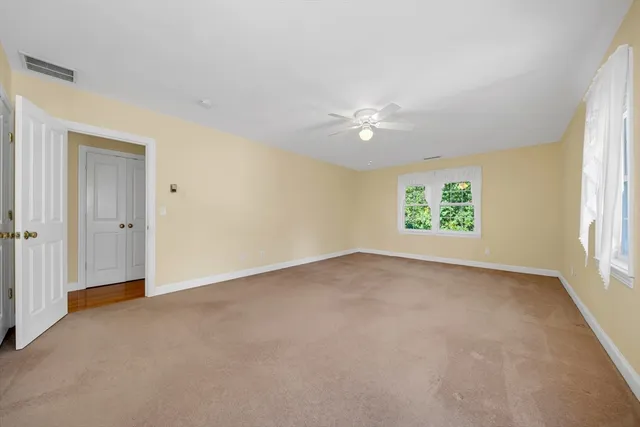 an empty room with windows and chandelier fan