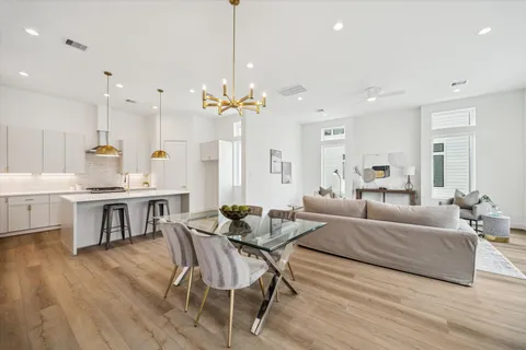 a living room with furniture kitchen view and a wooden floor