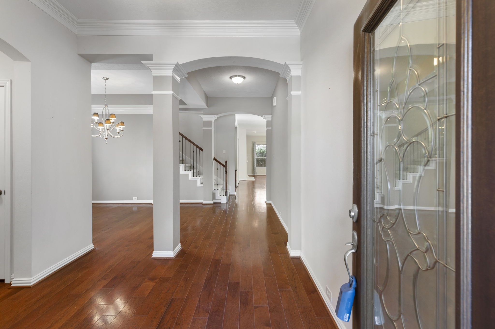 80 West Frontera Circle Spring, TX 77382 - Photo 2 of 28 Expansive entryway with hardwood floors and crown molding. The open layout leads to a formal dining area with chandelier and a wrought iron staircase