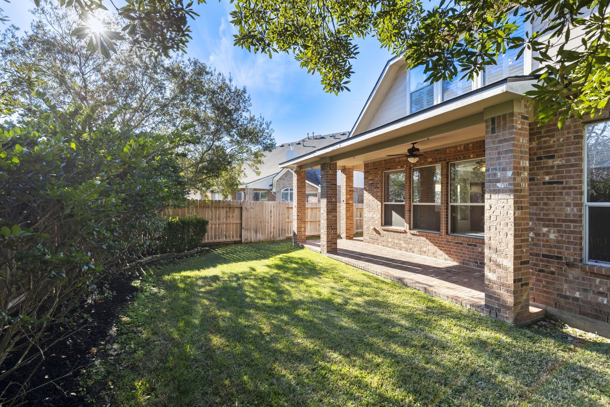 80 West Frontera Circle Spring, TX 77382 - Photo 27 of 28 Charming backyard with a well-maintained lawn, a brick patio, and wrap around covered porch, perfect for outdoor relaxation, outdoor meals, shaded playtime, and evening relaxation surrounded by mature trees, providing privacy and a serene atmosphere.