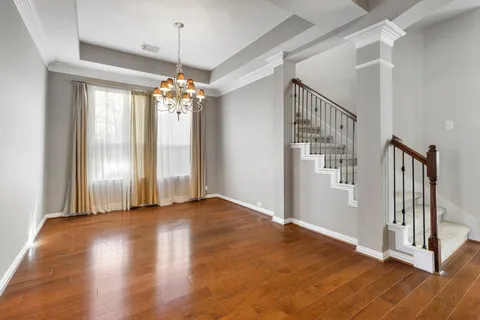 a view of a room with wooden floor chandelier and windows