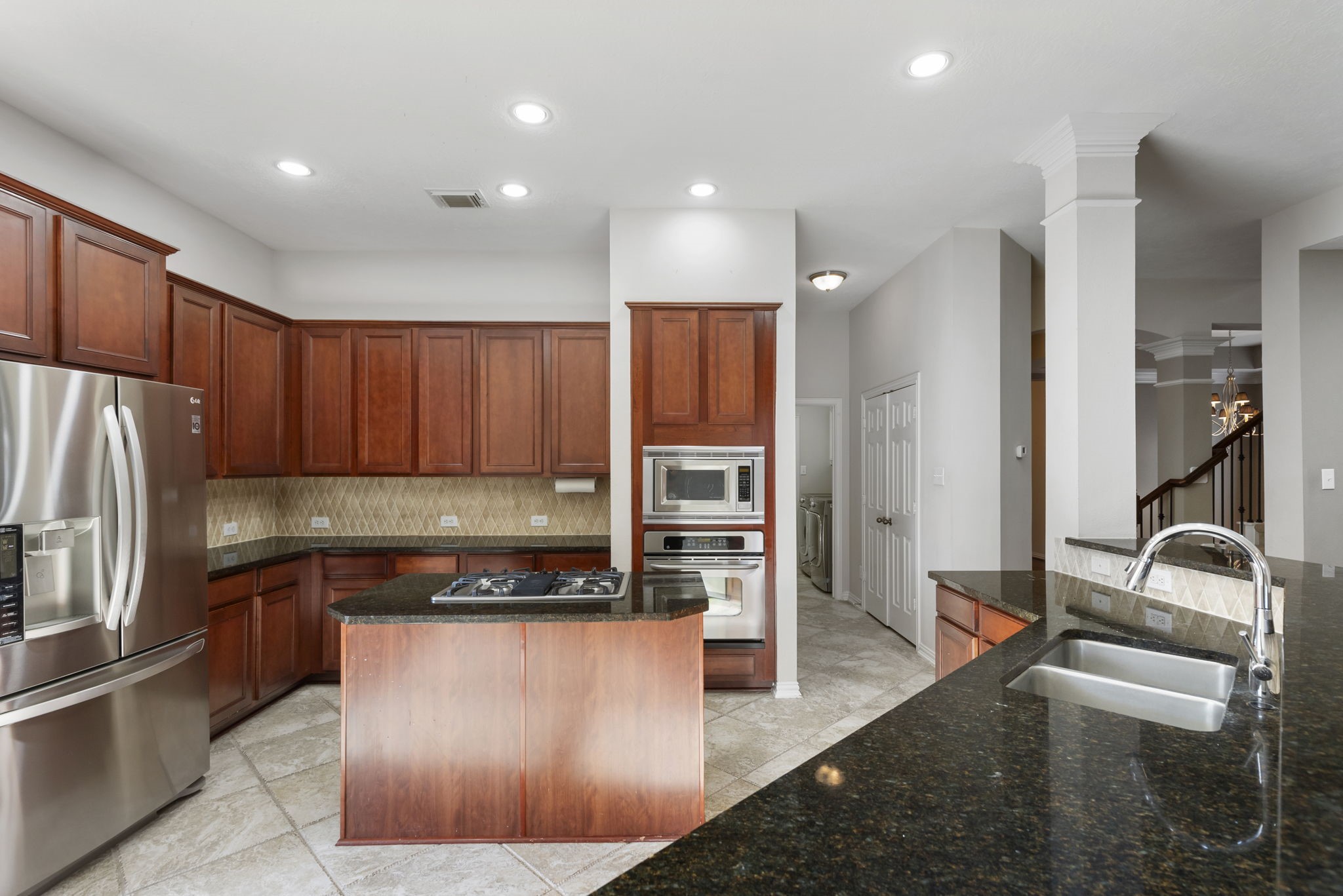 80 West Frontera Circle Spring, TX 77382 - Photo 7 of 28 Ample counters space and plenty of cabinets for a chef's kitchen. Complete with gas cooktop island. Notice the walkway that leads to the pantry, MUD builtin, laundry, and garage.