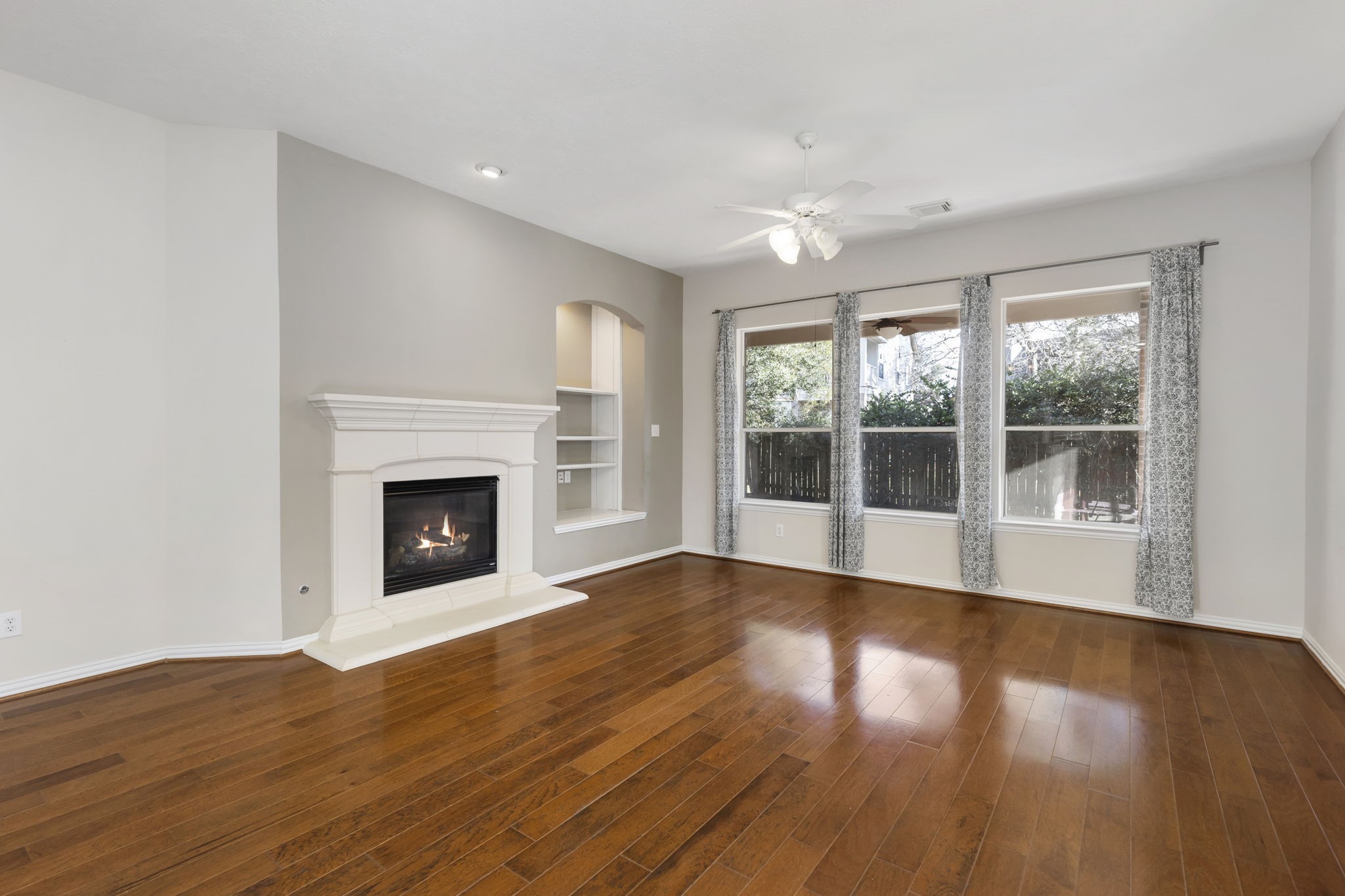 80 West Frontera Circle Spring, TX 77382 - Photo 10 of 28 This inviting living room features hardwood floors, a cozy fireplace with a mantel, built-in shelving, and large windows offering ample natural light and views of the outdoor greenery.