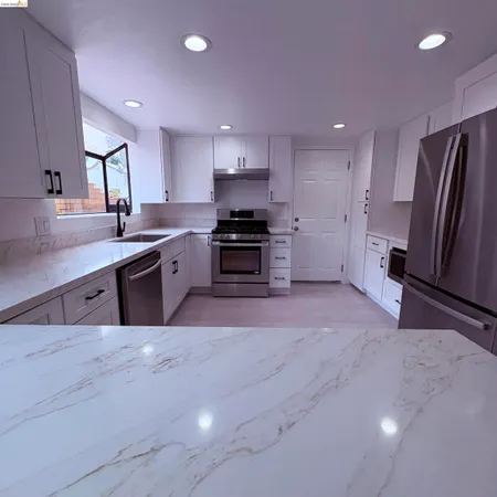 a large kitchen with stainless steel appliances a stove a sink a refrigerator and a oven