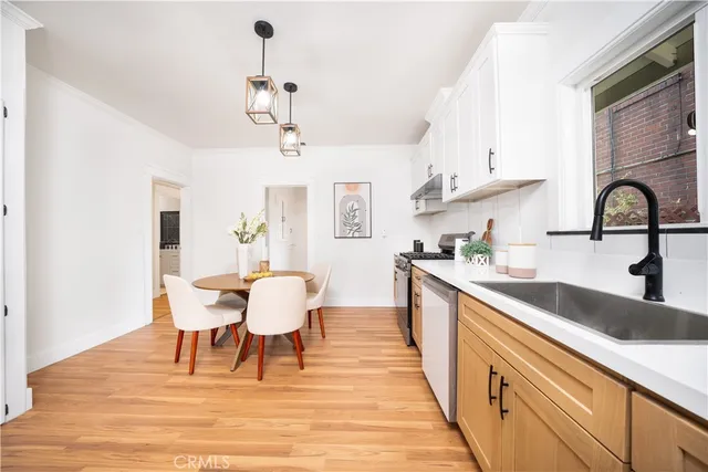 a kitchen with stainless steel appliances granite countertop a dining table chairs a sink and dishwasher a refrigerator with wooden floor