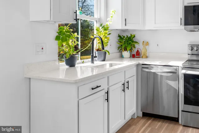 a kitchen with stainless steel appliances white cabinets sink and wooden floor