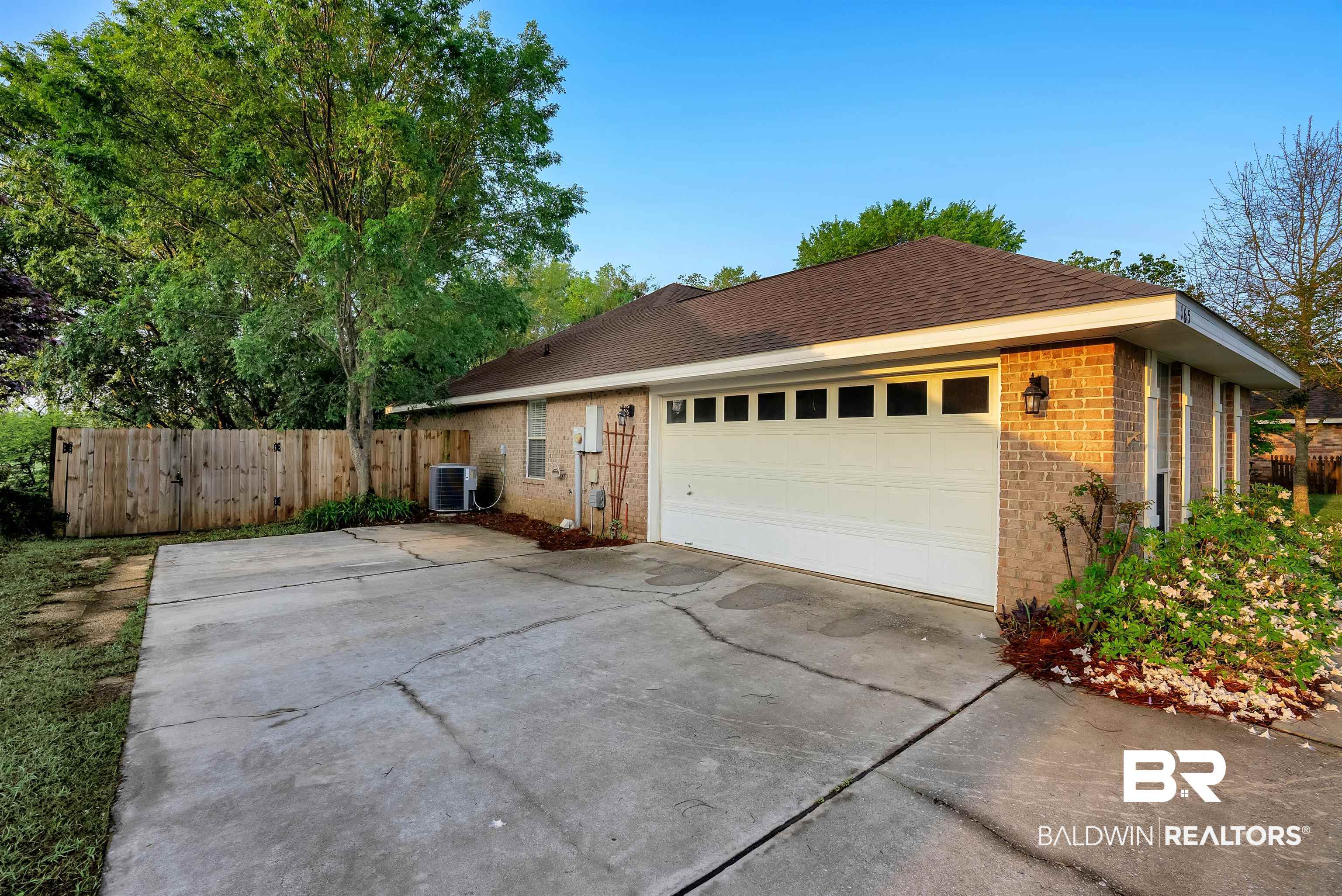 165 Pemberton Loop Fairhope, AL 36532 - Photo 24 of 25 View of side of home featuring concrete driveway, cooling unit, an attached garage, fence, and brick siding