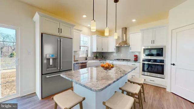 a kitchen with stainless steel appliances kitchen island a table chairs sink and cabinets