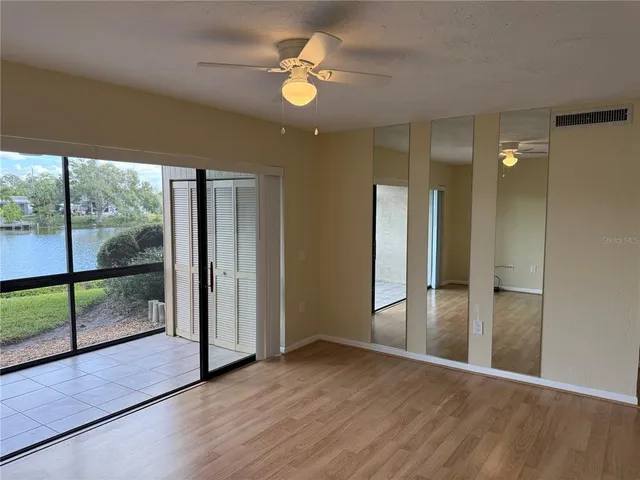 a view of empty room with wooden floor and fan