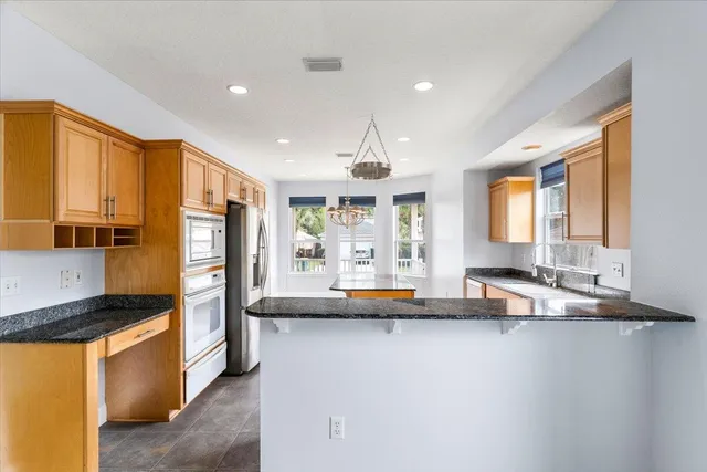 a kitchen with stainless steel appliances granite countertop a sink refrigerator and cabinets