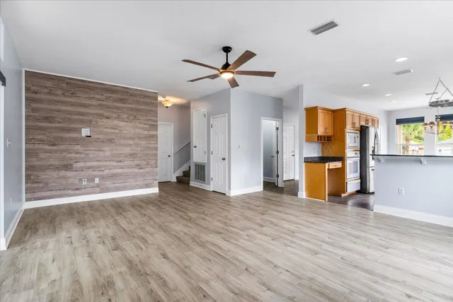 an empty room with wooden floor fan and windows