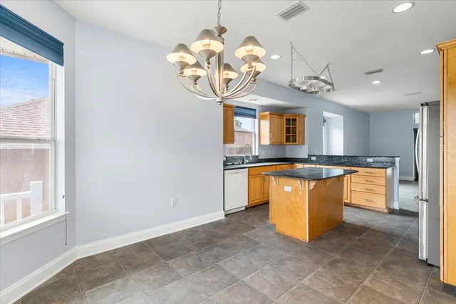 a kitchen with stainless steel appliances granite countertop a refrigerator a sink dishwasher a oven a dining table and chairs with wooden floor