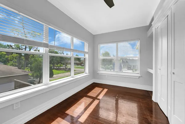 an empty room with wooden floor and windows