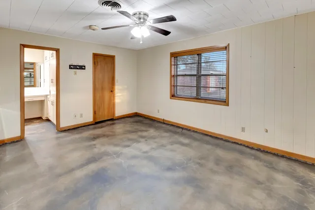 an empty room with a ceiling fan and carpet