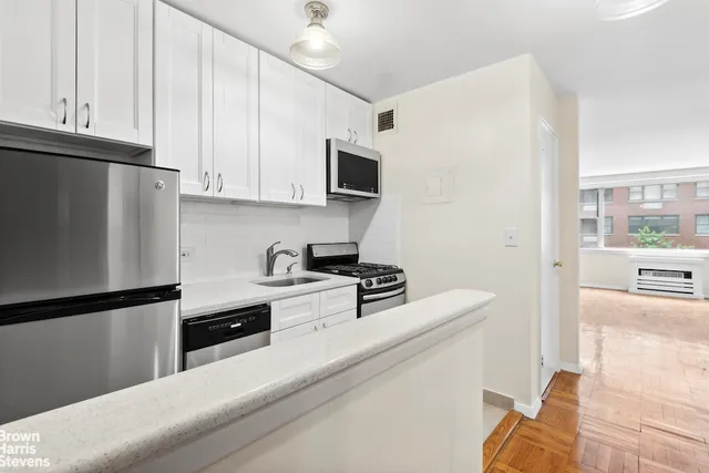 a kitchen with stainless steel appliances white cabinets and a refrigerator