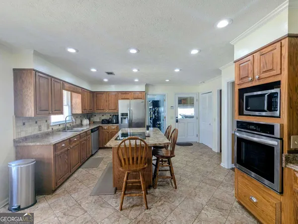 a kitchen with kitchen island granite countertop wooden cabinets dining table and stainless steel appliances