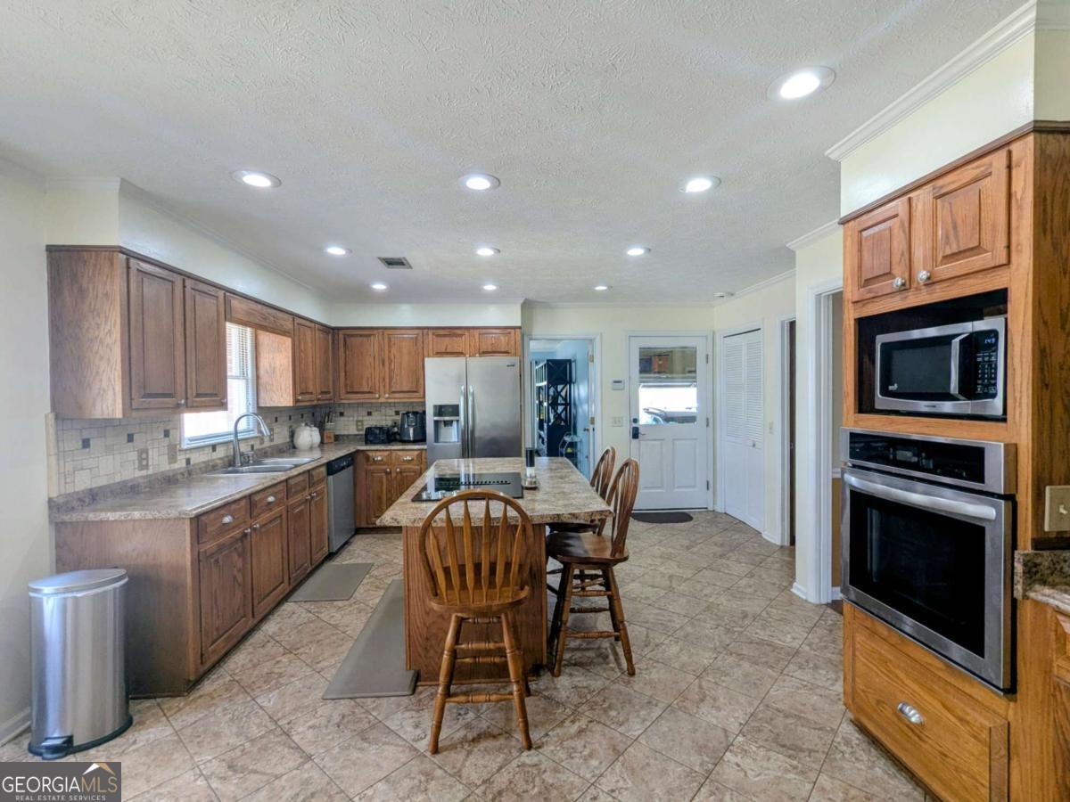 2005 Adams Street Vidalia, GA 30474 - Photo 16 of 50 a kitchen with kitchen island granite countertop wooden cabinets dining table and stainless steel appliances