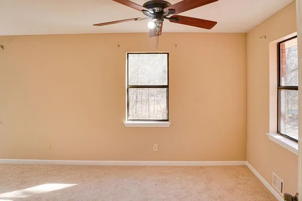 an empty room with windows and fan