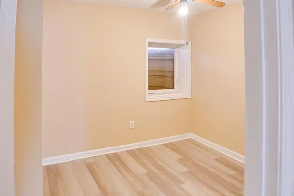 a view of an empty room with wooden floor and a window