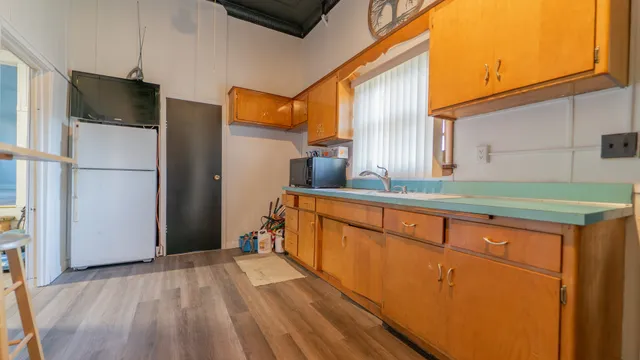 a kitchen with stainless steel appliances granite countertop a refrigerator a stove and a sink with wooden floor