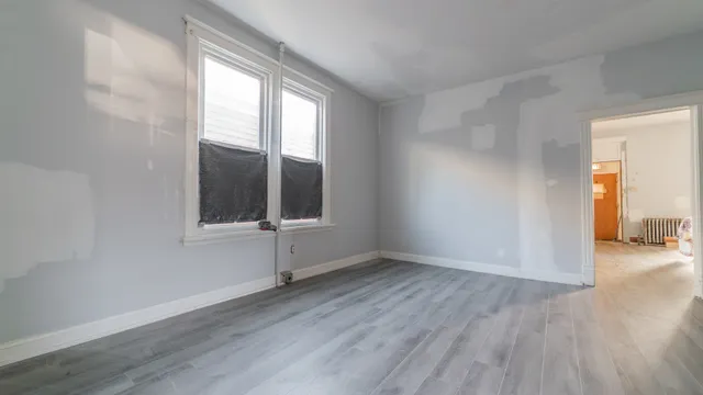 an empty room with wooden floor and windows