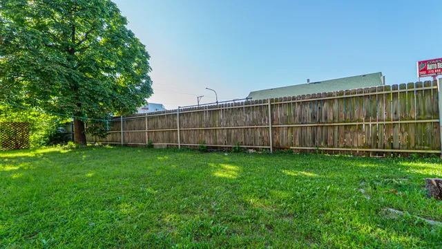 a view of a backyard with wooden fence and a bench