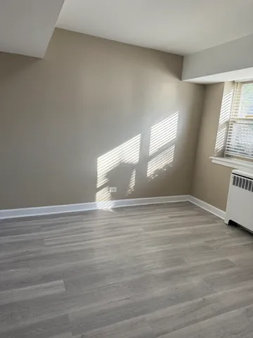 a view of empty room with window and wooden floor