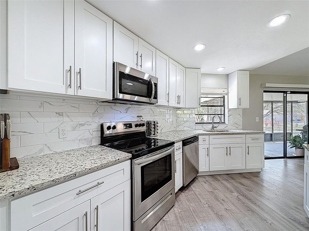 5384 Baldock Avenue Spring Hill, FL 34608 - Photo 23 of 51 a kitchen with granite countertop white cabinets appliances a window and a counter space