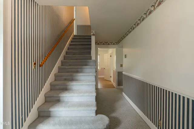 a view of staircase with lots of frames on wall and wooden floor