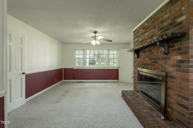 a view of an empty room with a fireplace and a window