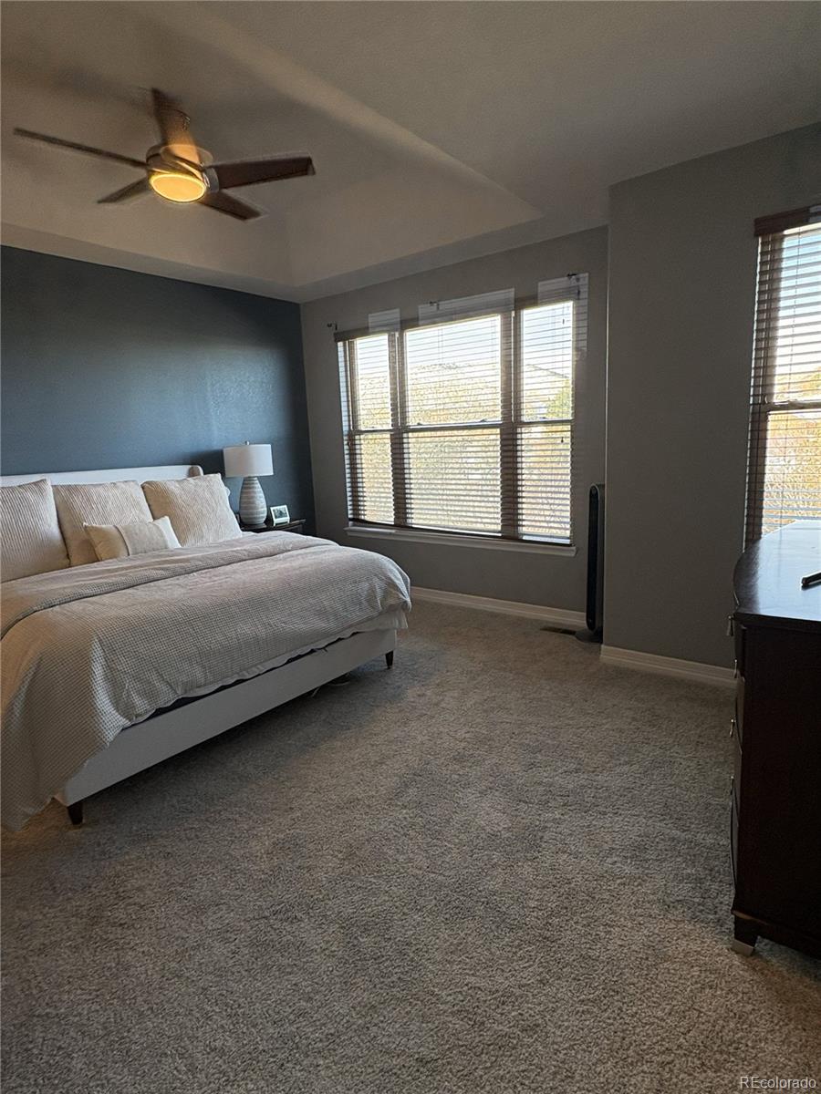10158 RidgeGate Circle Lone Tree, CO 80124 - Photo 11 of 15 a spacious bedroom with a bed and a chandelier
