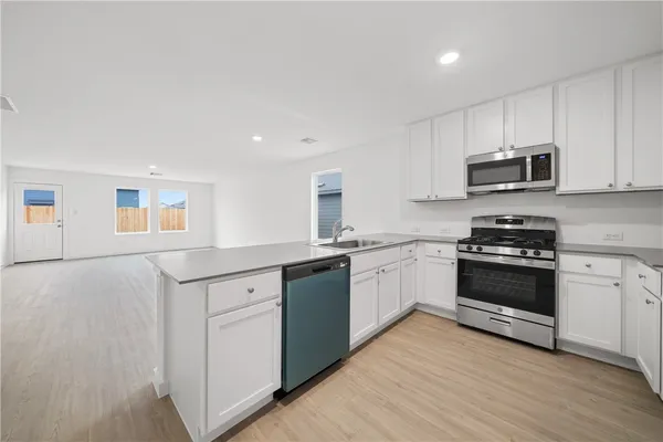 a kitchen with granite countertop white cabinets and stainless steel appliances