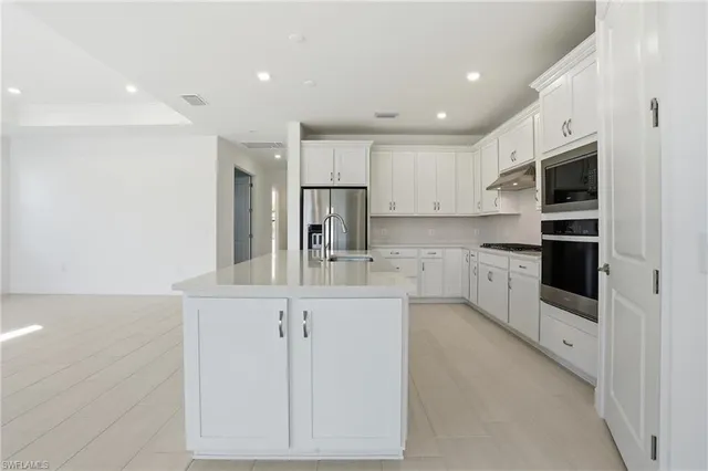 a kitchen with stainless steel appliances kitchen island sink refrigerator and cabinets