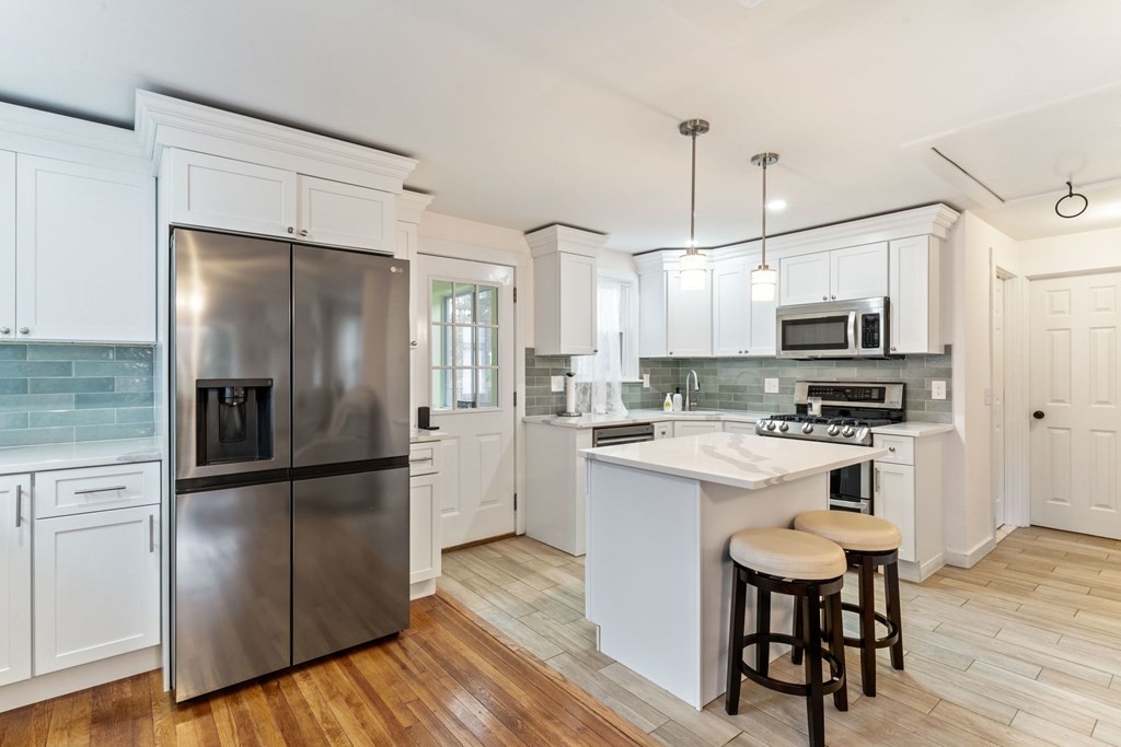 7 Meadowbrook Lane Ashland, MA 01721 - Photo 11 of 18 a kitchen with stainless steel appliances a refrigerator stove microwave and cabinets with wooden floor
