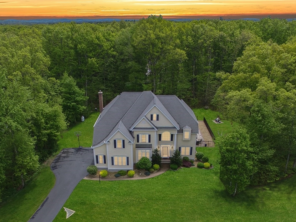 a aerial view of a house next to a big yard and large trees