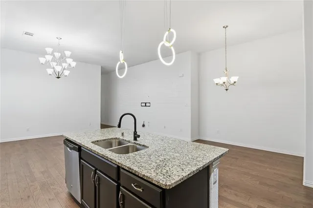 a kitchen with a sink chandelier and wooden floor