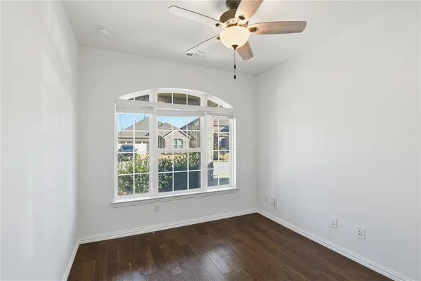 an empty room with wooden floor fan and a window
